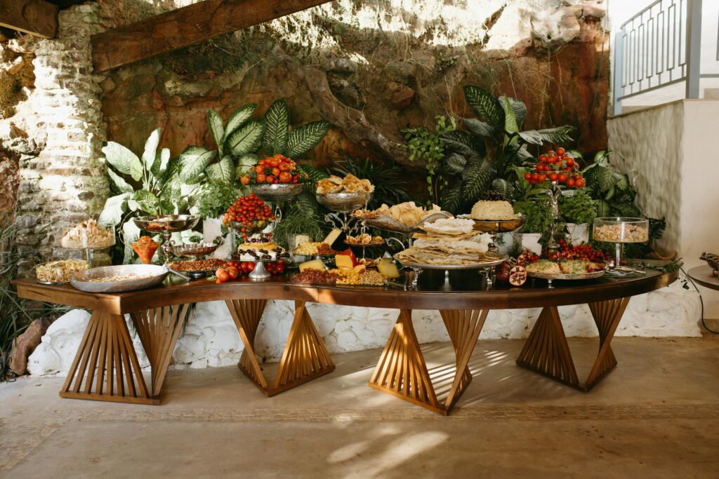 A lavish buffet table with assorted foods and vibrant greenery background.